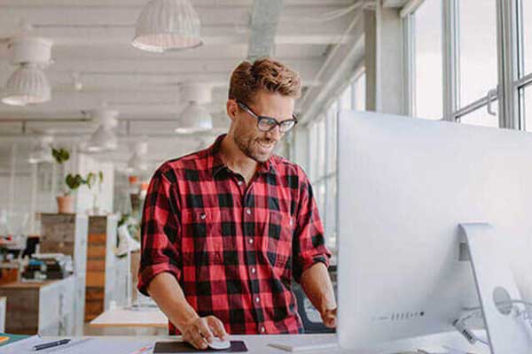 man in red and black plaid shirt working on a desktop computer