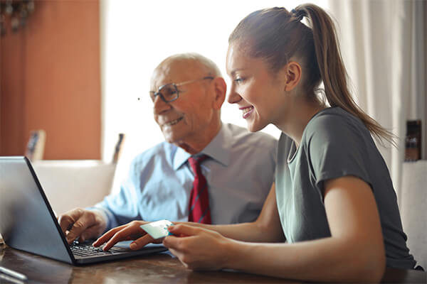 young woman and older man using a laptop